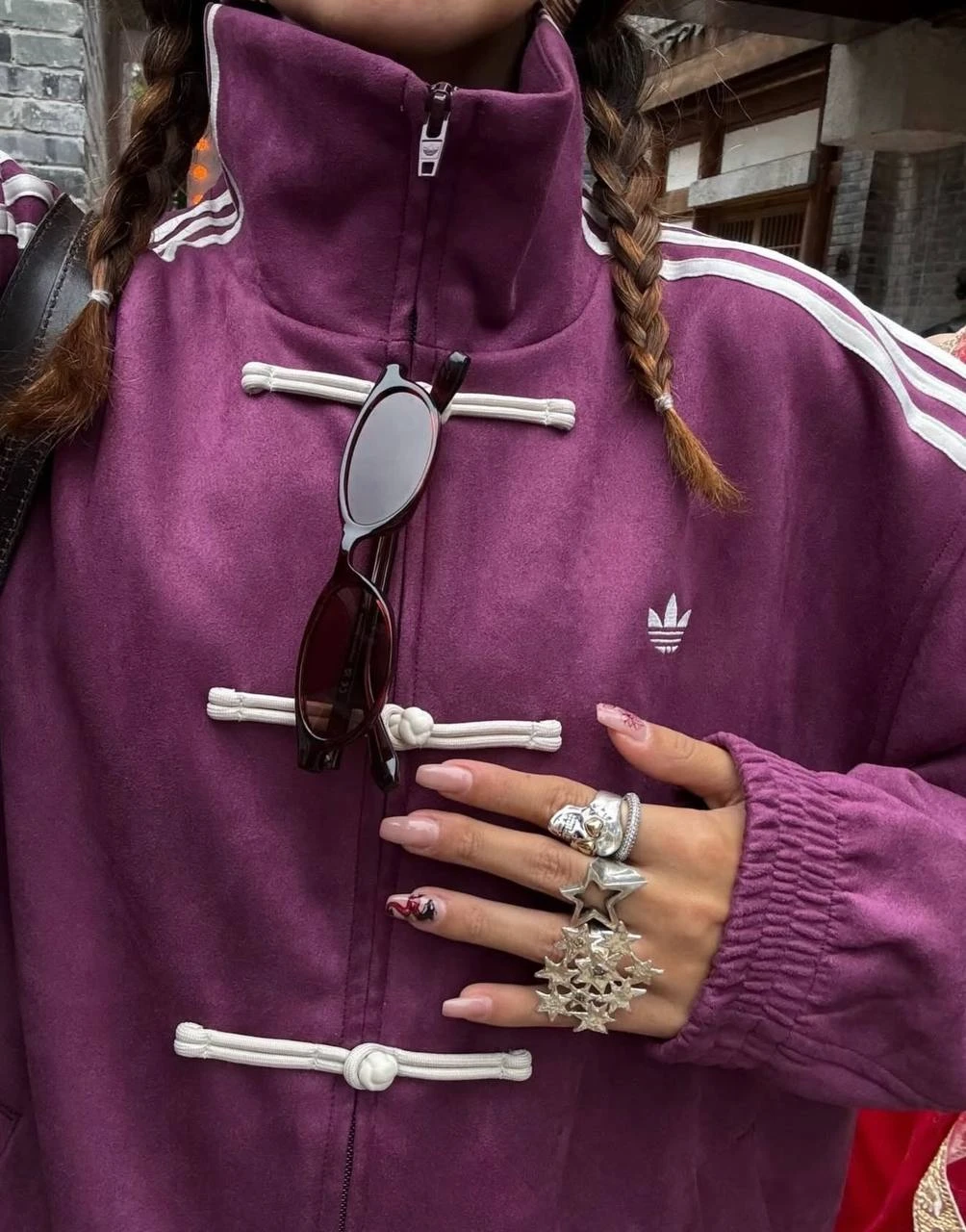 Крупный план пурпурного Adidas Tang Jacket: белые узловые застёжки панькоу, воротник-стойка и логотип Originals